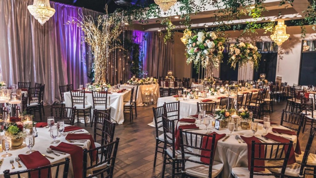 Elegant wedding reception setup at Chandelier Event Venue with floral centerpieces, crystal chandeliers, and candlelit tables.