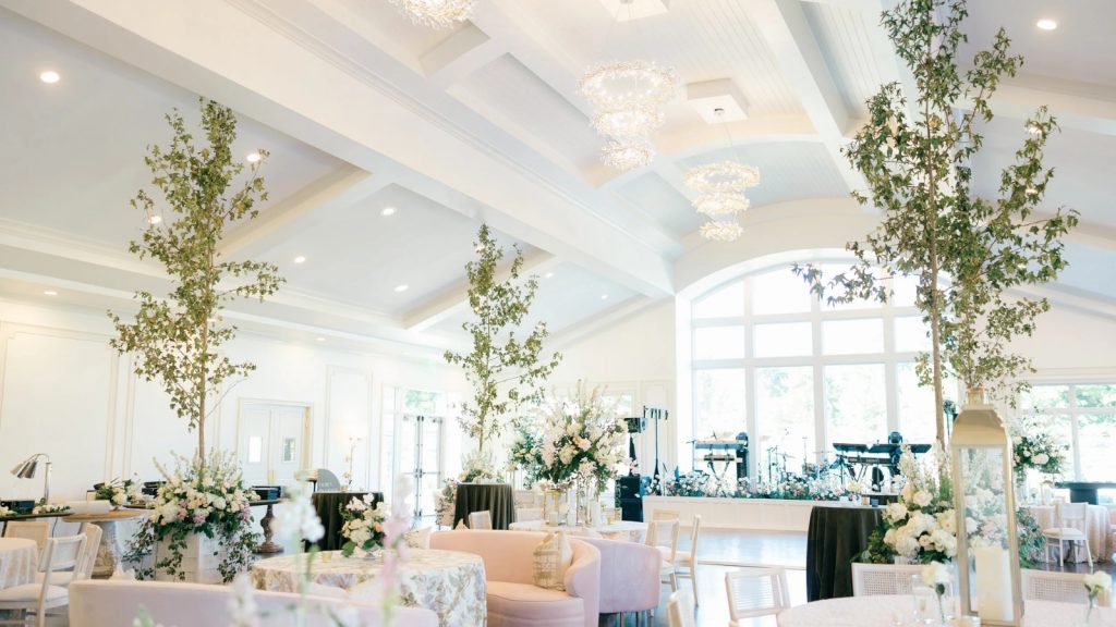 Elegant reception hall at Donovan Manor with floral centerpieces, chandeliers, and natural light from large windows.