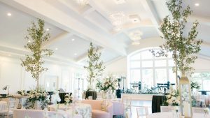 Elegant reception hall at Donovan Manor with floral centerpieces, chandeliers, and natural light from large windows.