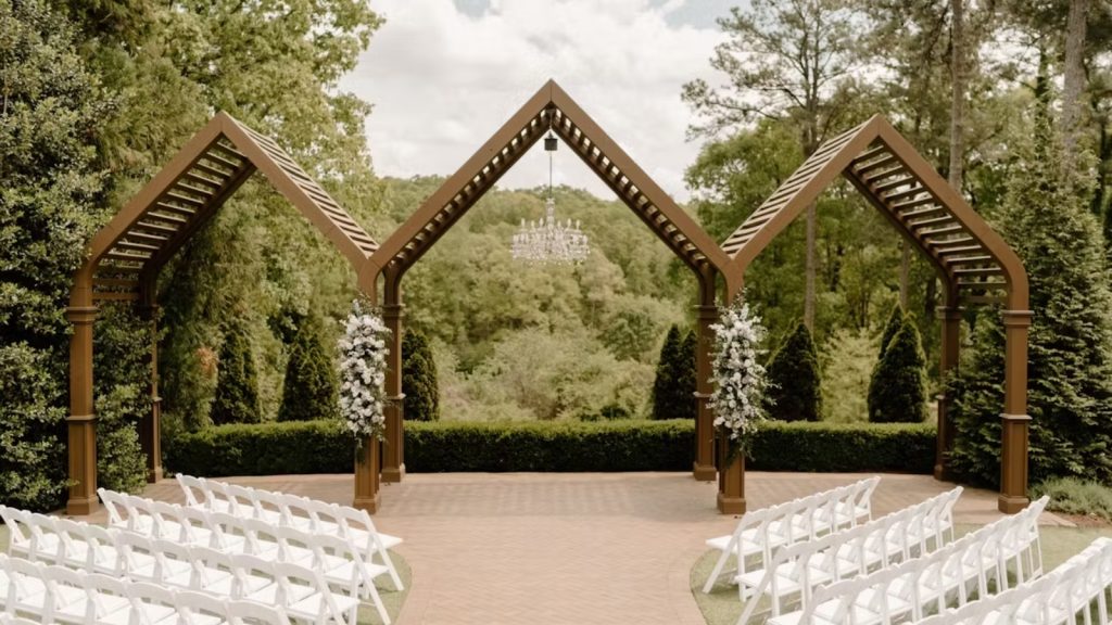 Outdoor wedding ceremony setup at High Grove Estate with white chairs, floral arrangements, and a wooden arbor.