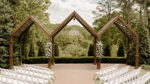 Outdoor wedding ceremony setup at High Grove Estate with white chairs, floral arrangements, and a wooden arbor.