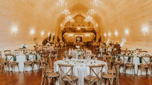 Wedding reception setup inside the Historic Wakefield Barn with round tables, chandeliers, and elegant rustic décor.