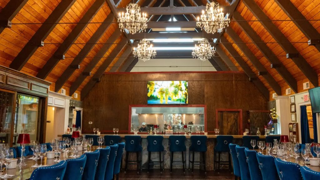 Elegant tasting room at JOLO Winery and Vineyards with chandeliers, wood-beamed ceilings, and a wine bar setup.