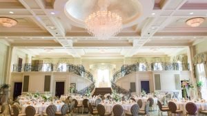 Elegant wedding reception setup at Prestwood Country Club with chandeliers, round tables, and a grand double staircase.