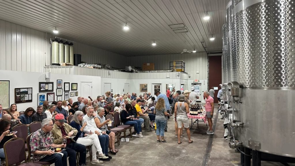 Guests gather inside the production facility at Raffaldini Vineyards & Winery for a wine event with stainless steel tanks in view