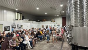 Guests gather inside the production facility at Raffaldini Vineyards & Winery for a wine event with stainless steel tanks in view