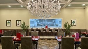Elegant dining area at Rayson Winery & Vineyards with Bistro Europa Restaurant featuring a crystal chandelier, modern seating, and an open kitchen view.